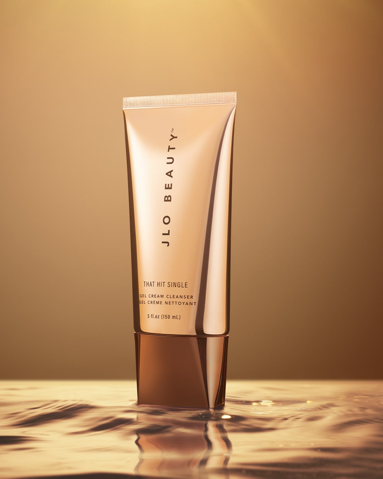 Tube of JLO Beauty gel cream cleanser product on a reflective surface with a gradient background